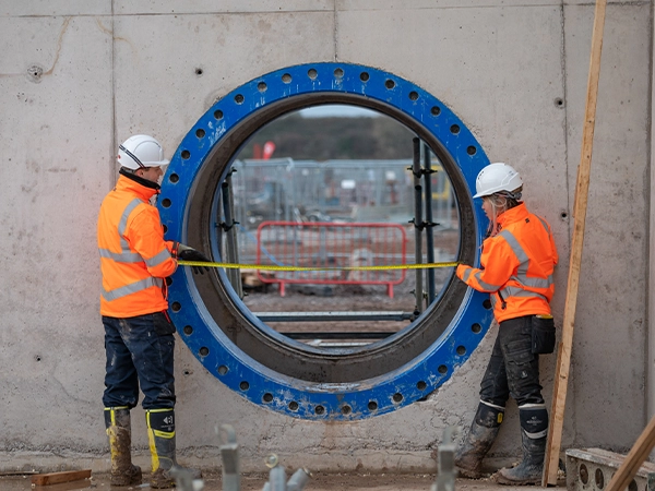 Construction workers in PPE on site, measuring